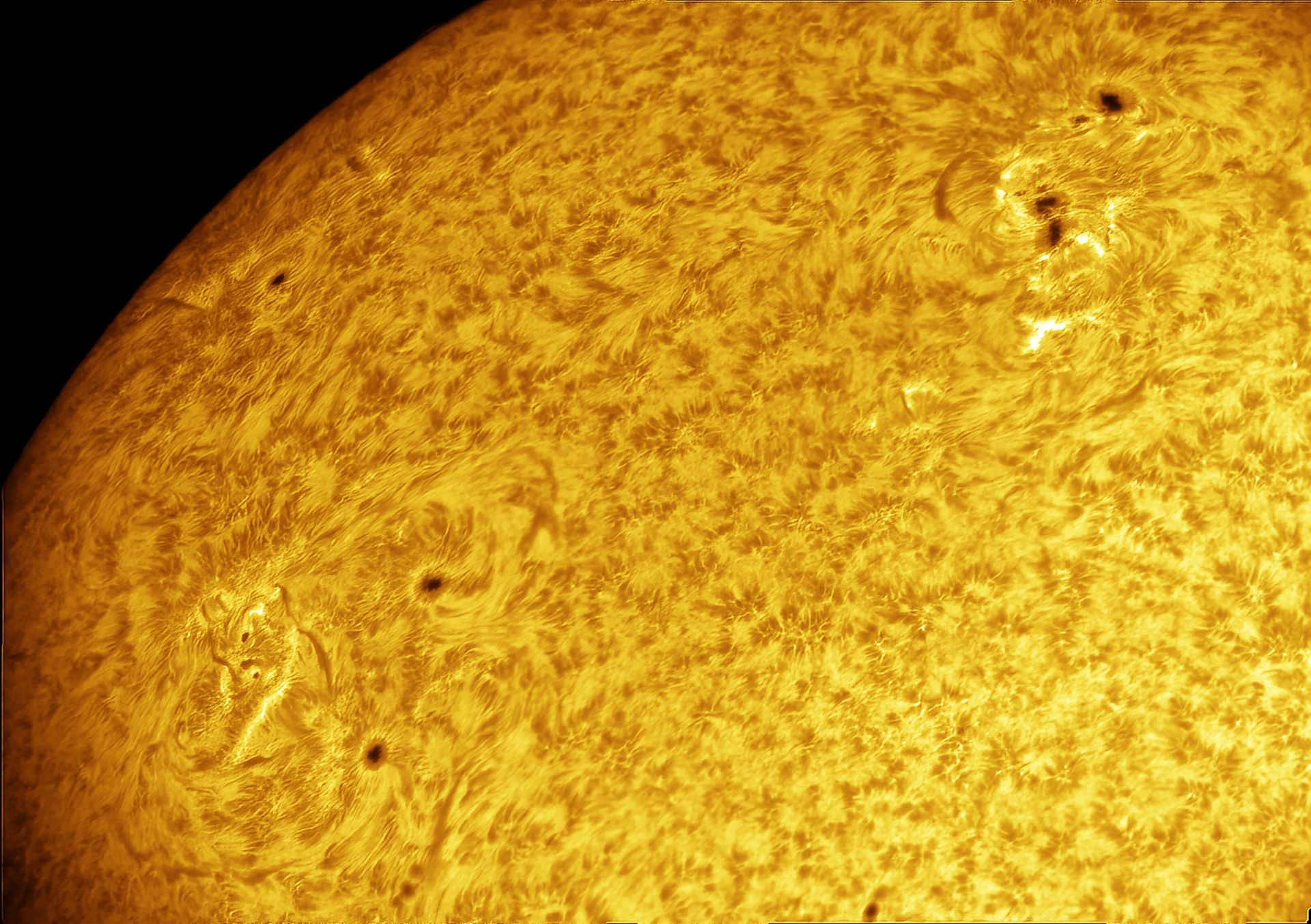 Borde del Sol y parte de su superficie. Se observan manchas solares, algunas tan grandes que superan el diámetro de la Tierra. En la esquina superior derecha y en la inferior izquierda aparecen unas estructuras oscuras con forma de nubes llamadas filamentos. En realidad, son las mismas estructuras de plasma que las protuberancias solares, pero vistas desde otra perspectiva: en lugar de observarlas sobresaliendo del borde del Sol, las vemos proyectadas sobre su superficie.
