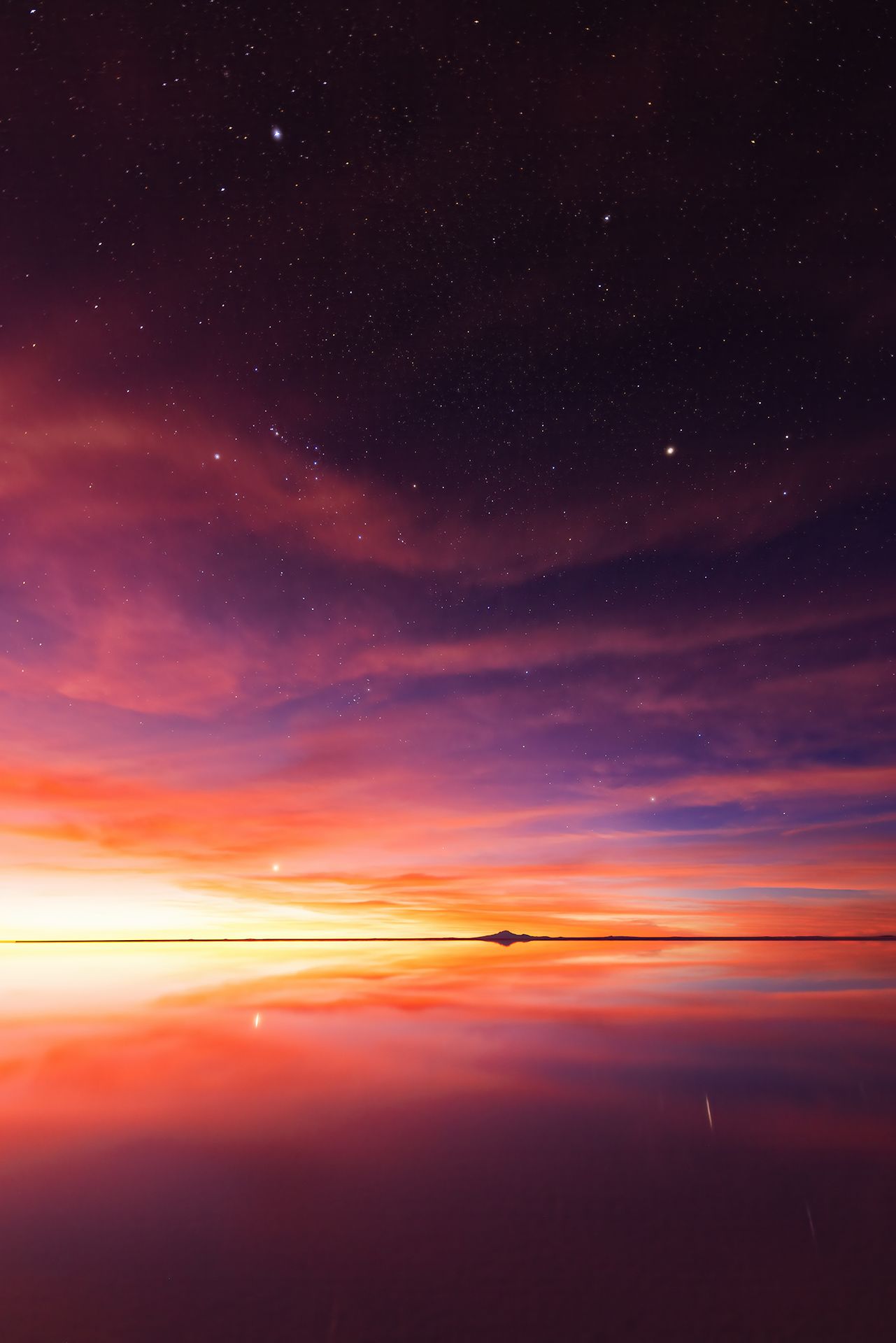 Los atardeceres se funden con la noche y comienzan a verse las estrellas. La imagen muestra un paisaje particular, con el reflejo del cielo sobre el agua hasta el horizonte, en el Salar de Uyuni.
