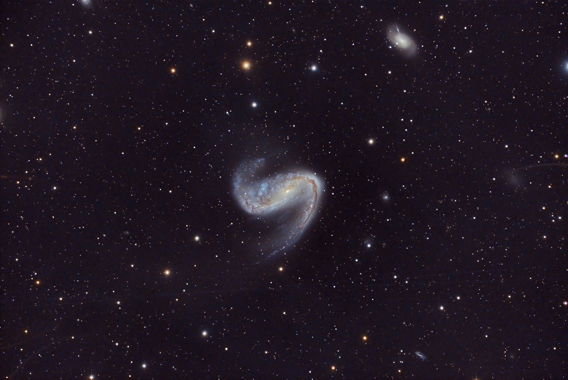 NGC 2442 es una galaxia espiral ubicada en la constelación de Volans, a unos 50 millones de años luz. Destaca por su forma asimétrica, similar a un gancho de carnicero, probablemente causada por interacciones gravitacionales pasadas con una galaxia más pequeña.