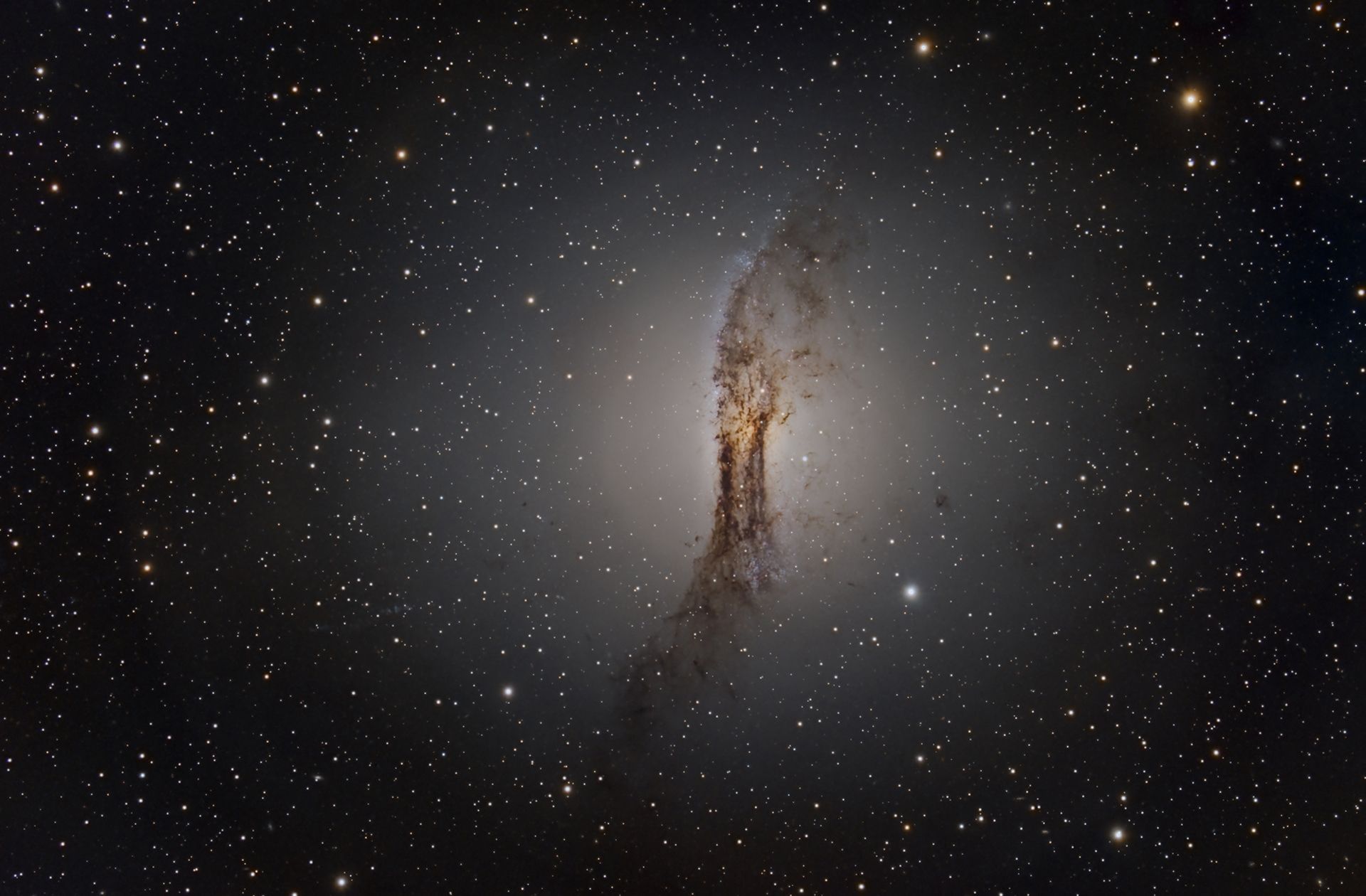 La galaxia Centaurus A (NGC 5128) es la quinta galaxia más brillante del cielo. En cielos oscuros puede observarse con binoculares de buen aumento como una pequeña mancha borrosa. Ubicada a unos 12 millones de años luz, se formó por la colisión de dos galaxias y es reconocible por su banda de polvo oscuro y su brillante núcleo elíptico.